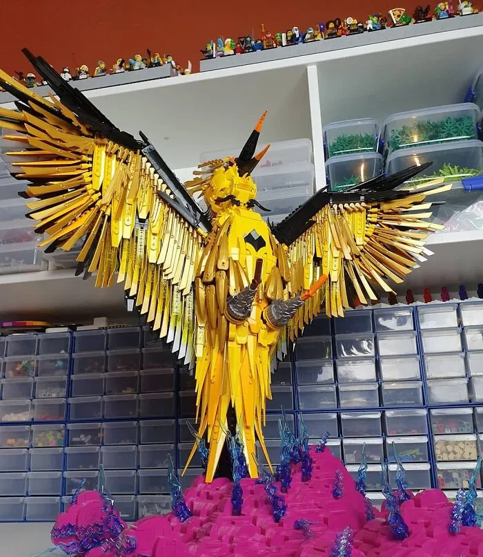 Intricate LEGO builds of a large yellow bird with spread wings displayed on colorful base, showcasing incredible LEGO art skills.