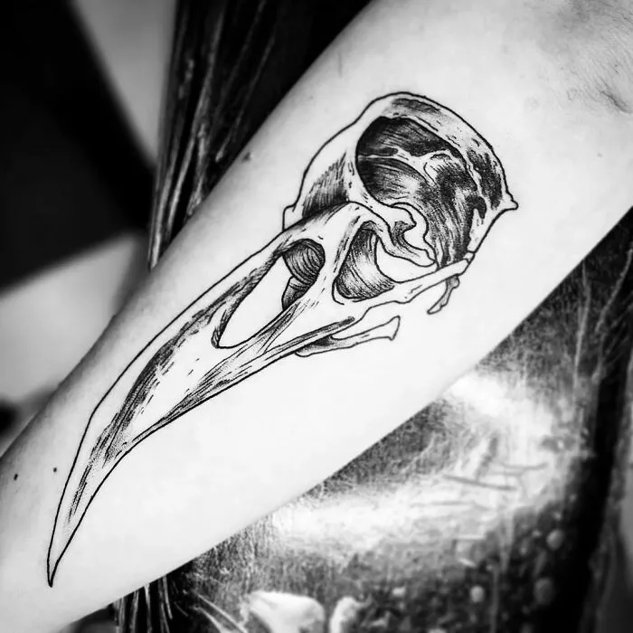 Marvel tattoo of a stylized bird skull on an arm, showcasing intricate linework.