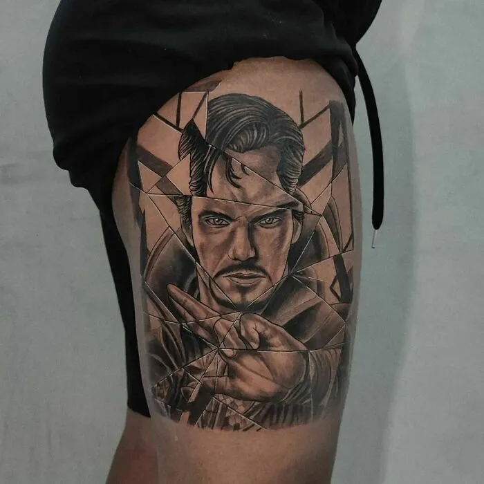 Marvel-inspired tattoo of a superhero Dr. Strange with a fragmented design on a person's thigh.