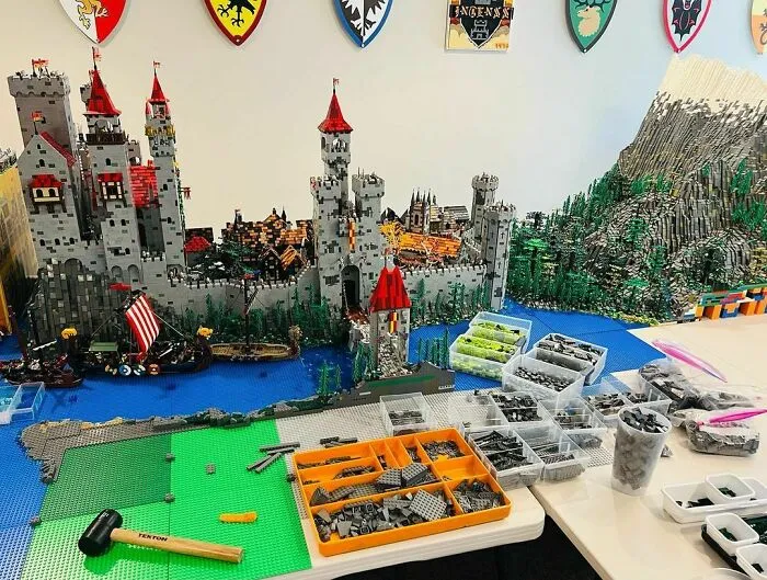 Intricate LEGO castle build with ships and mountains, showcasing incredible LEGO builds as detailed works of art on a table.