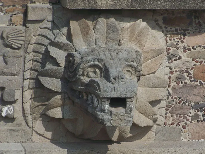 Rock statue of Feathered Serpent head on a wall 