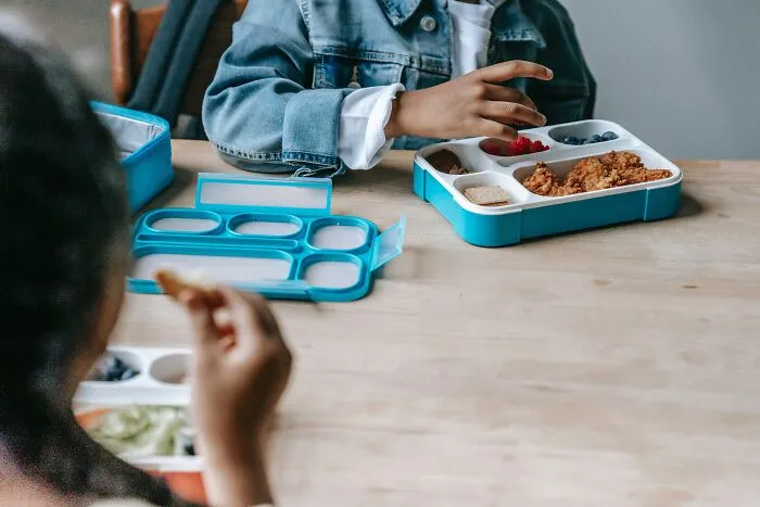 Kied Eating their Dinner From A Lunch Box 