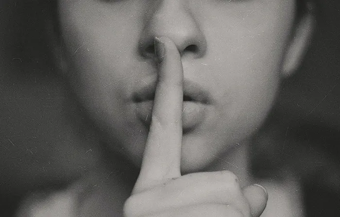 Woman holding her finger and making silence sign