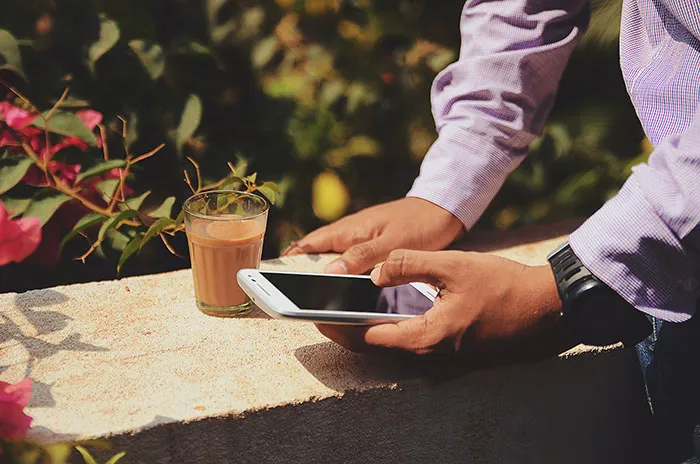 Person holding phone and coffee