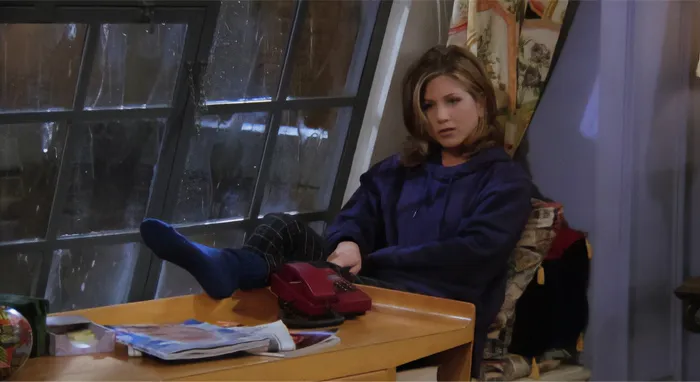Woman in casual clothes sitting by a window looking thoughtful, representing signs of a fake friend and toxic relationship