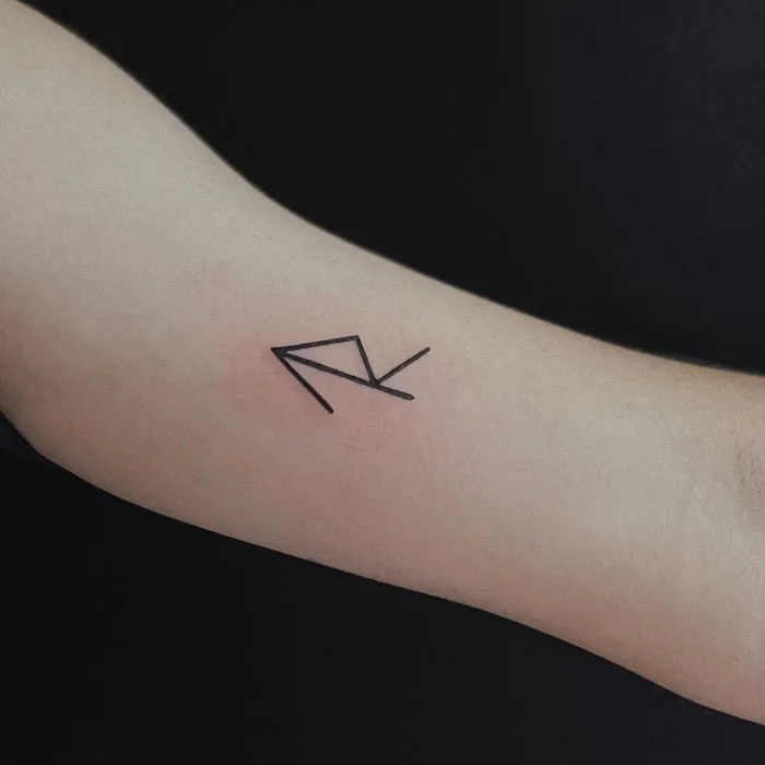 Minimalist tattoo of geometric lines on an arm against a dark background.