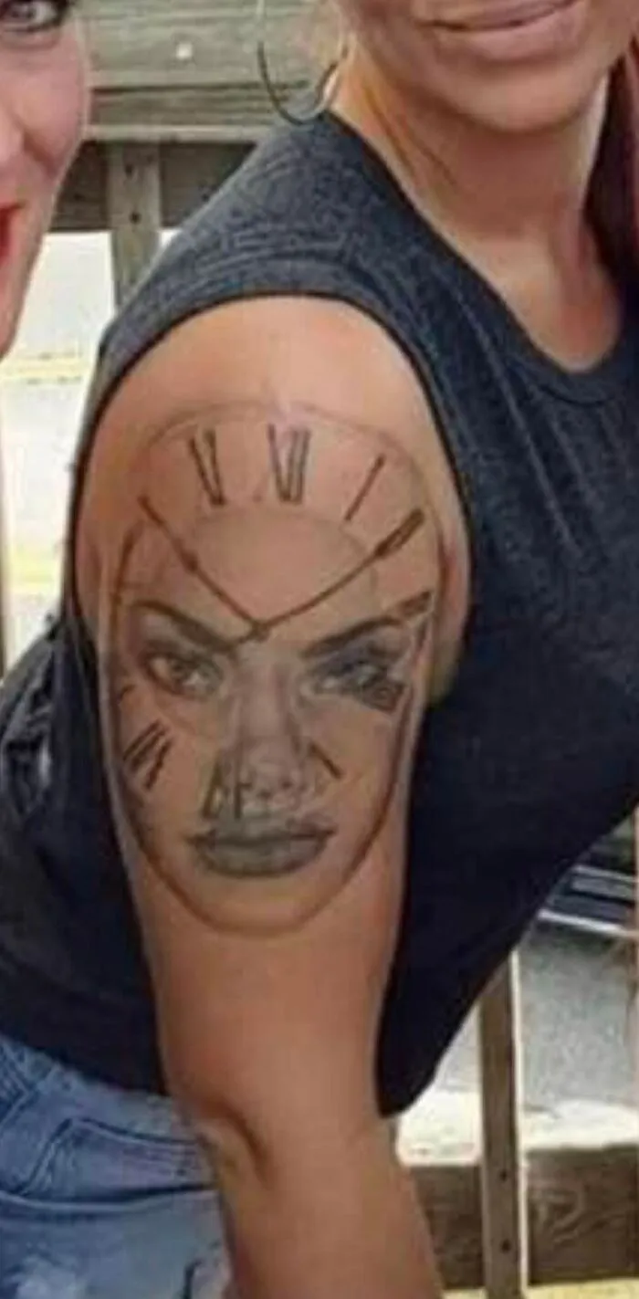 Tattoo of a face with clock design on a person's upper arm, showcasing unexpected tattoo art.