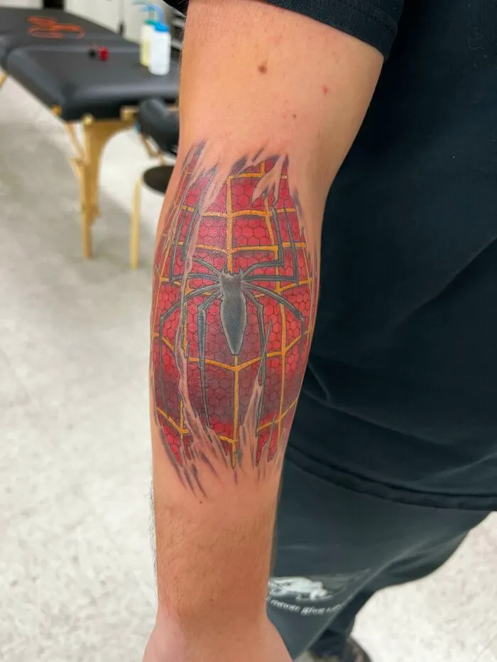 Marvel tattoo featuring a Spider-Man design on a person’s arm in a tattoo studio setting.