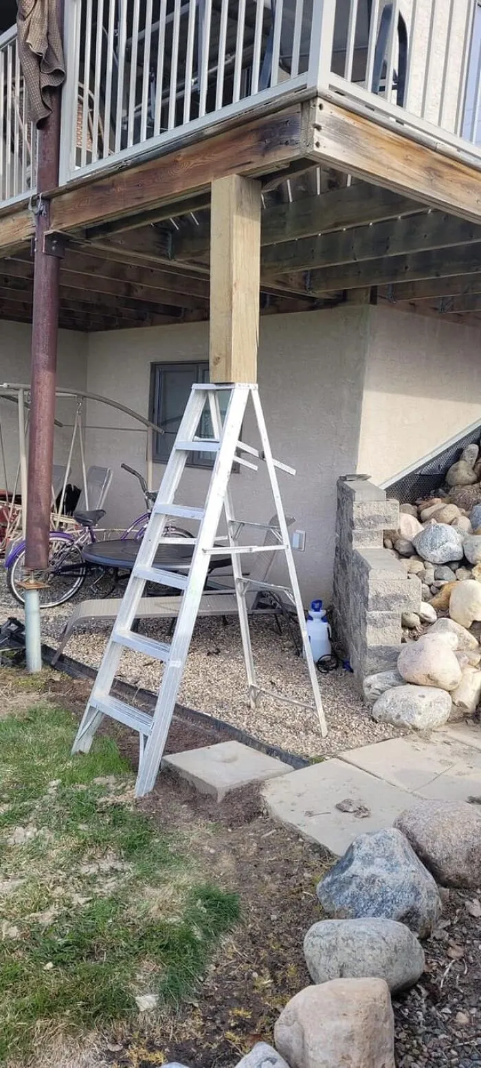 Ladder supporting a deck beam in a risky DIY setup, ignoring OSHA safety guidelines.