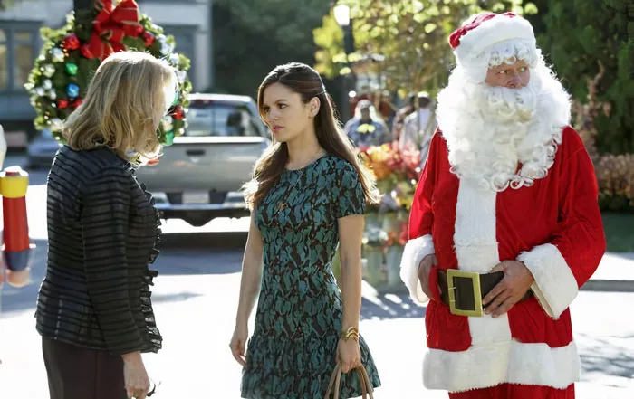 Zoe next to a man dressed as Santa Claus talking to a woman 