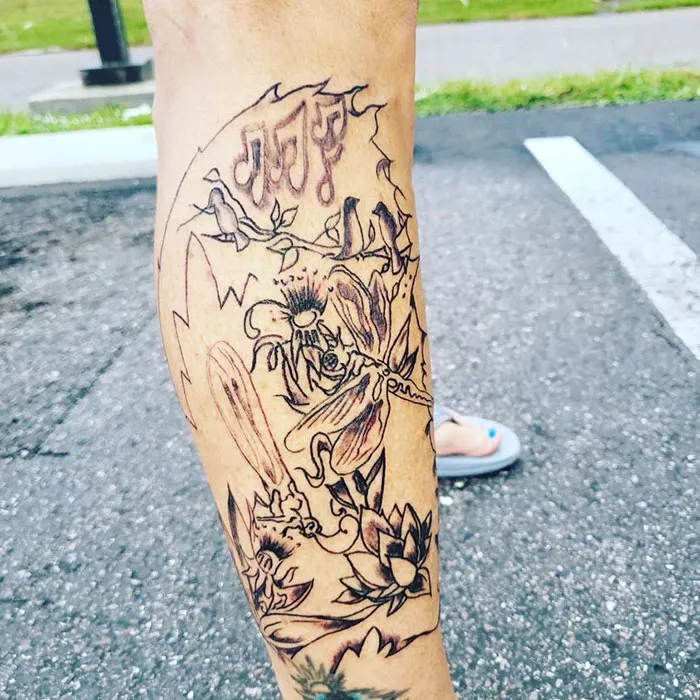 Abstract leg tattoo with flowers and music notes on pavement background, showcased in tattoo group.