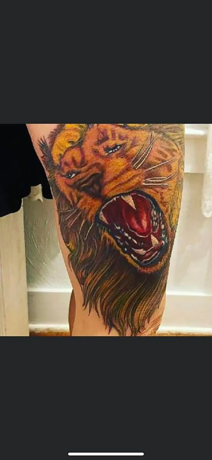 Lion tattoo on leg with bold colors and intricate details, showcasing an example of questionable tattoo art.
