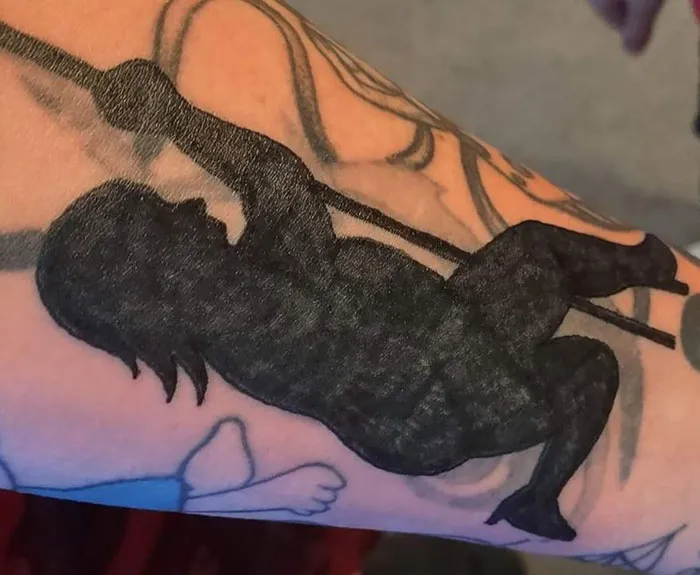 Silhouette tattoo on arm in awkward position, showcasing a poorly done design.