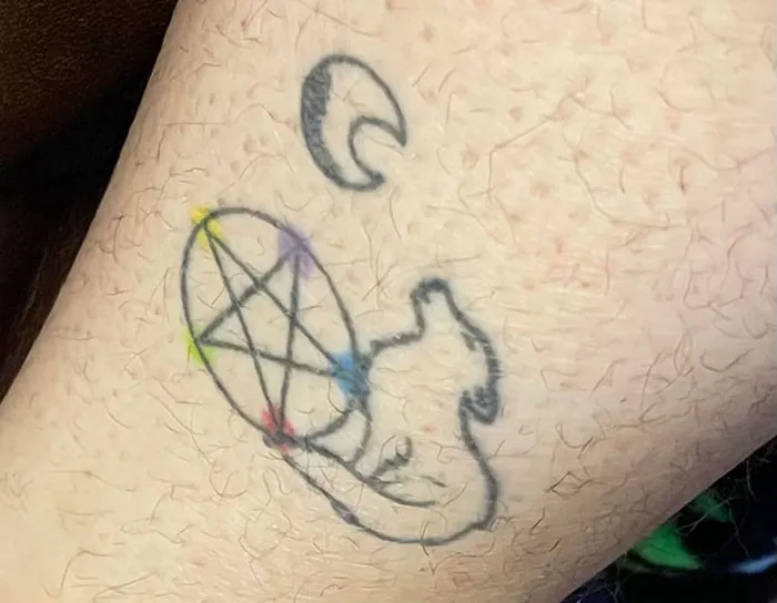 Bad tattoo with a poorly drawn pentagram and abstract shapes in faded ink.