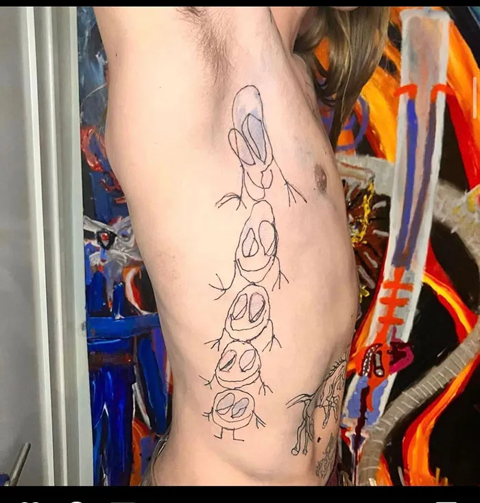 Bad tattoos example of shaky cartoonish figures inked on a person's side with colorful artwork in the background.