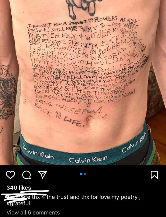 Chest tattoo with uneven text resembling poetry overlaid on skin.