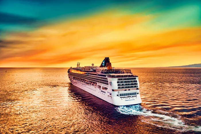 Cruise ship sailing in the sea under a vibrant sunset, perfect for solo travel and "me time" experiences.