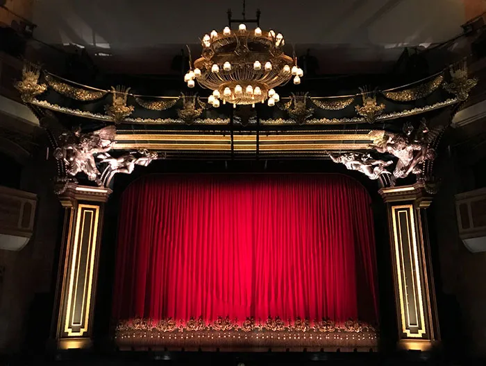 Theatre scene with ornate decor and red curtain, ideal for solo “me time” activities and personal enjoyment.