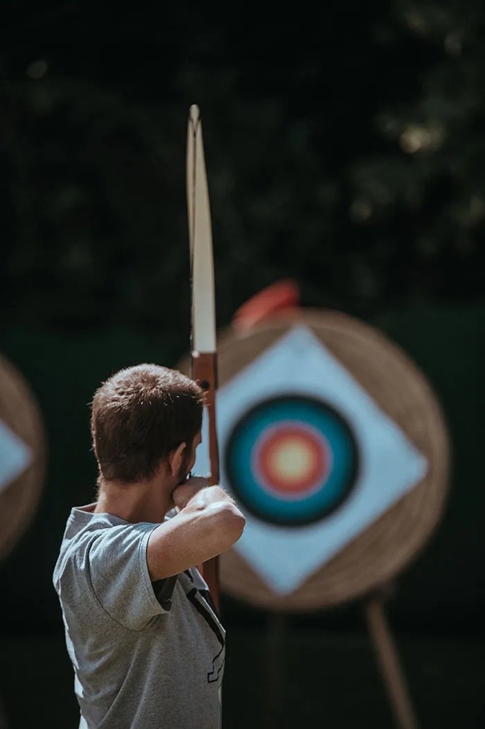 Person practicing archery alone at a target range, enjoying some "me time" with a bow and arrow.