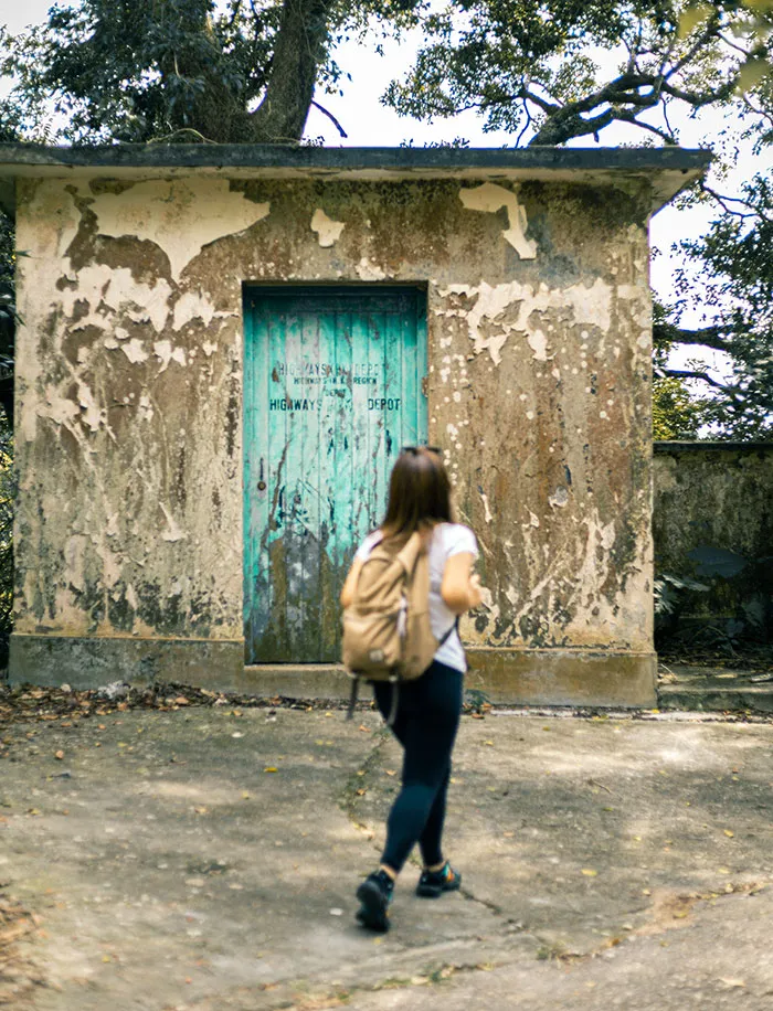 Woman enjoying geocaching adventure, exploring a weathered building for a solo "me time" experience.