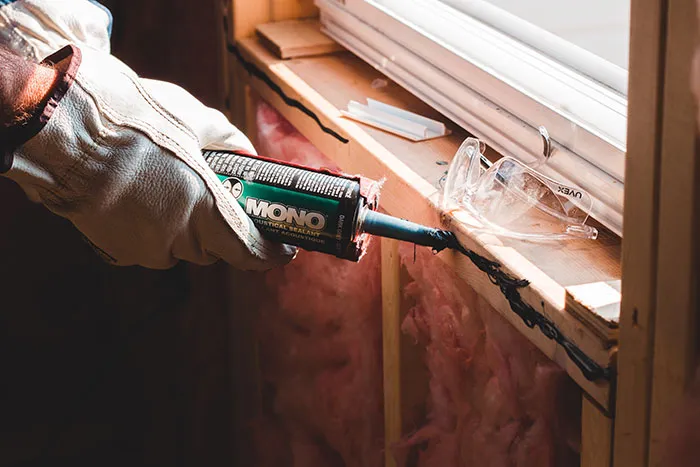 Person doing window repair alone, applying sealant to frame, wearing gloves, part of things to do for “me time.”