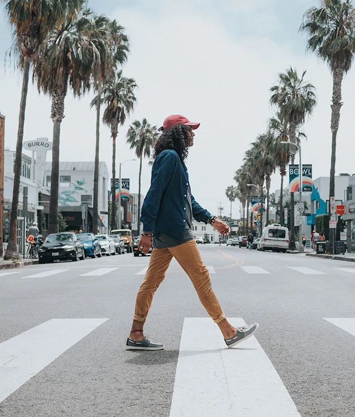 Person enjoying "me time" walking alone on a city street lined with palm trees.