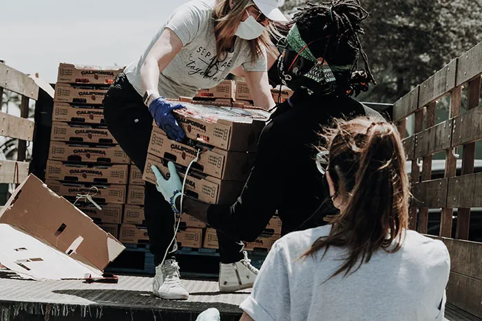 People collaborating to carry boxes, outdoors during the day, illustrating things to do by yourself for "me time".
