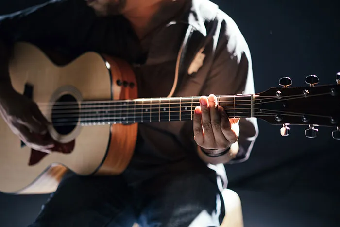 Person playing guitar for relaxing me time activity.