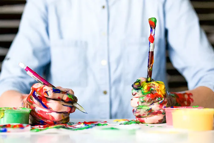 Person painting alone with colorful paint on hands, enjoying some me time.