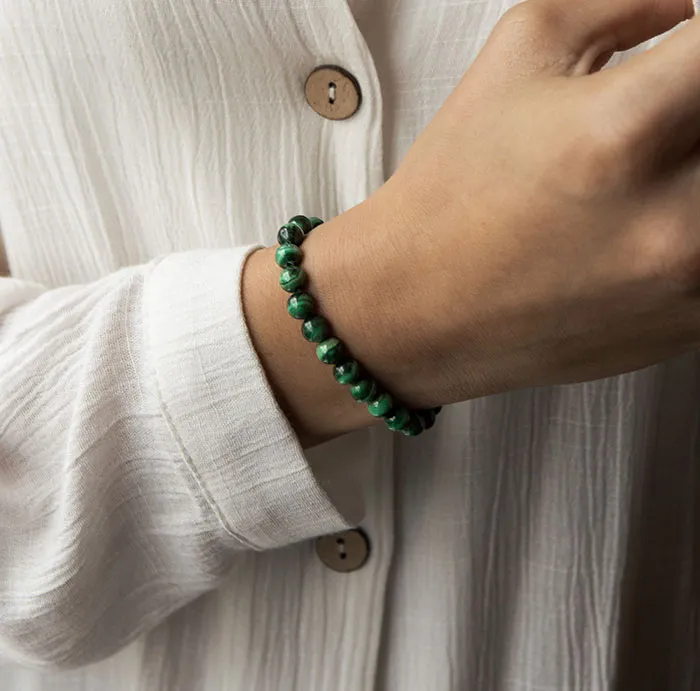 Woman enjoying me time, wearing a green bracelet and a white blouse, focusing on self-care.