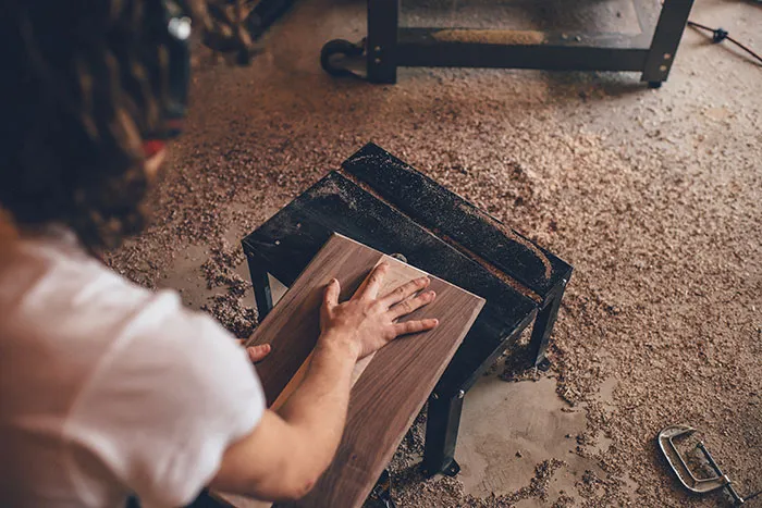 Individual sanding wood, enjoying me time by restoring furniture in a workshop setting.