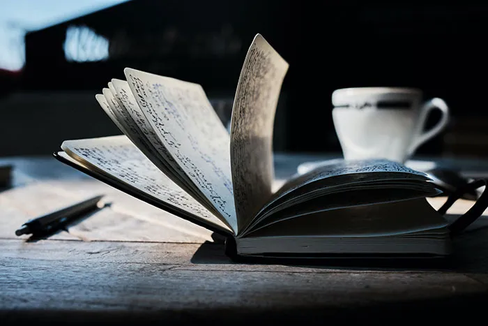 An open book on a wooden table with a coffee cup, perfect for enjoying me time activities.