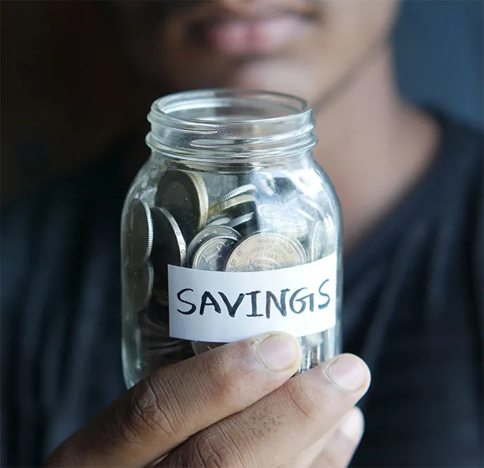 Person holding a jar labeled "savings," symbolizing financial self-care and solo activities.