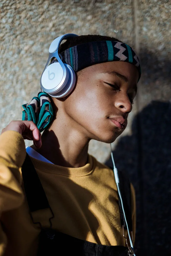 Person enjoying "me time" listening to music with headphones, eyes closed, wearing a yellow sweatshirt.