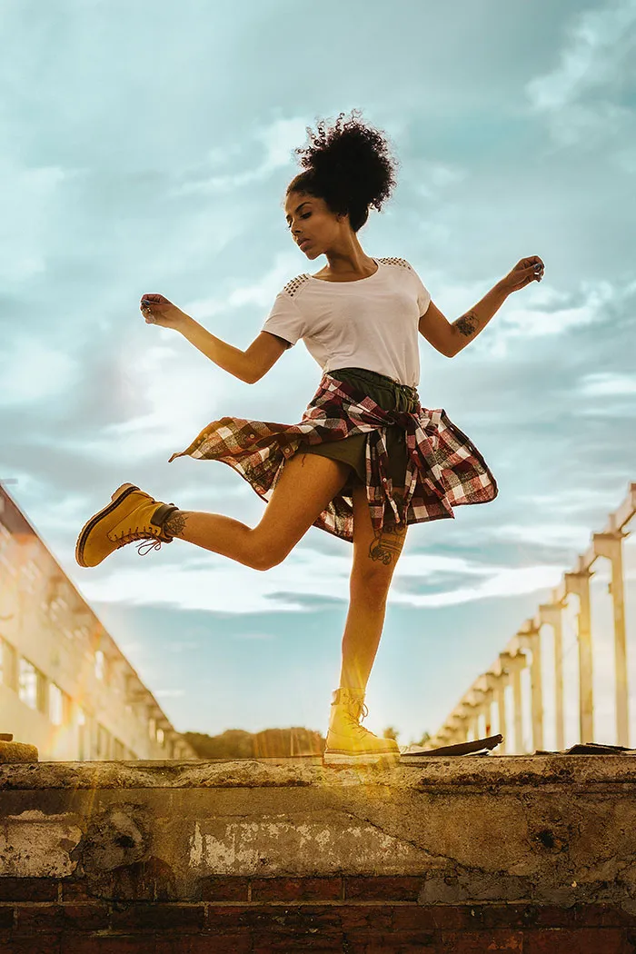 Person dancing joyfully alone outdoors, embracing "me time" under a vibrant sky.