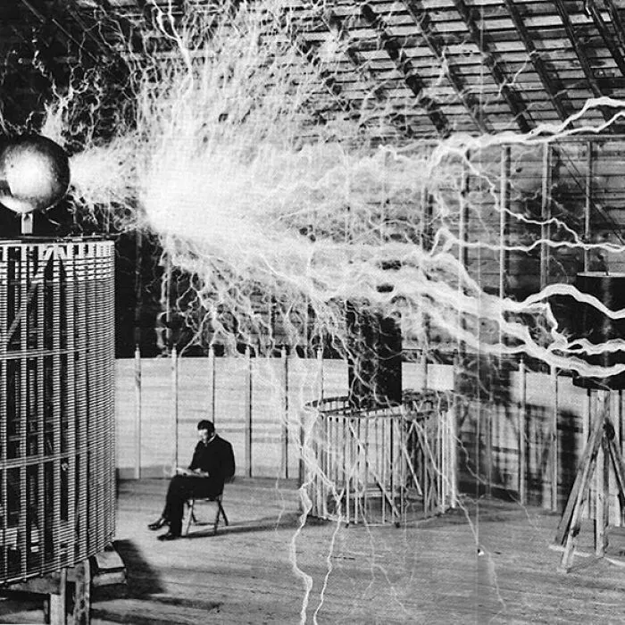 Nikola Tesla sentado en su laboratorio con su “transmisor de lupa”, diciembre de 1899 