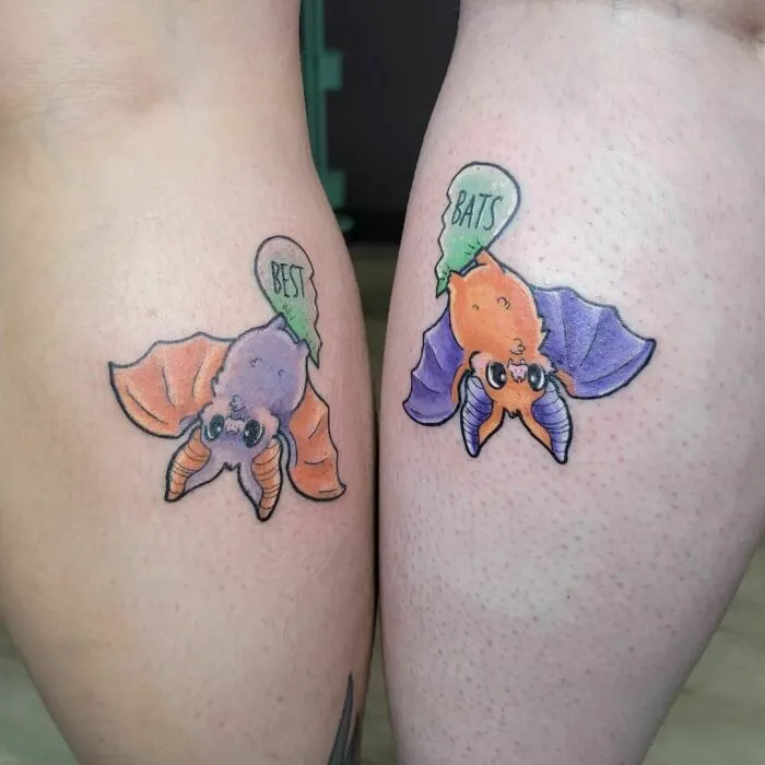 Colorful best friend tattoos of cartoon bats on two people.