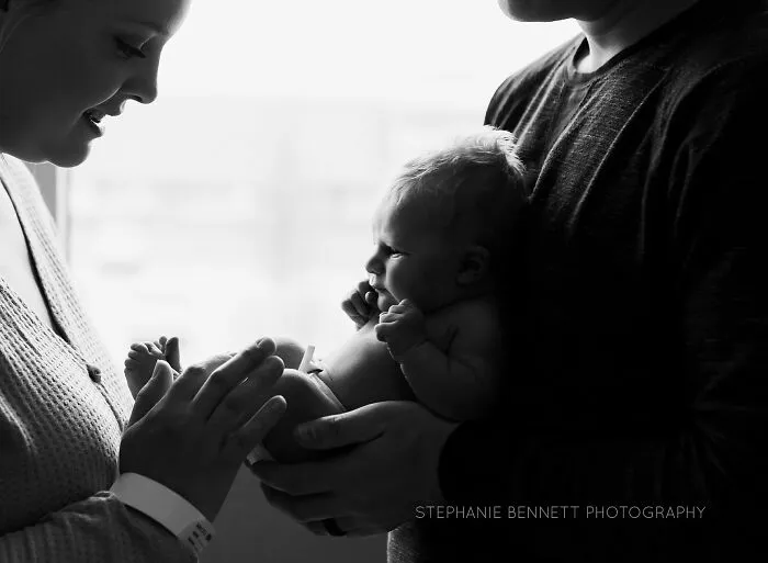A photograph of a newborn with their parents