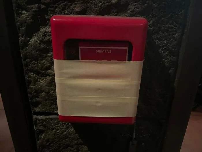 Fire alarm covered with tape, disregarding OSHA safety regulations.
