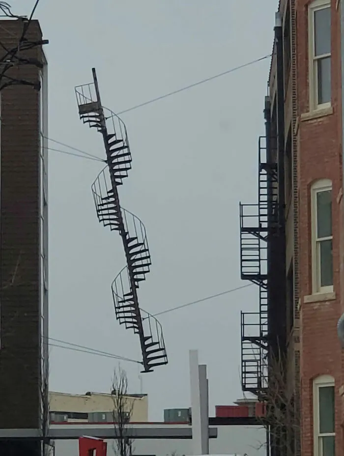 Unsafe staircase suspended between two buildings defies OSHA safety regulations.