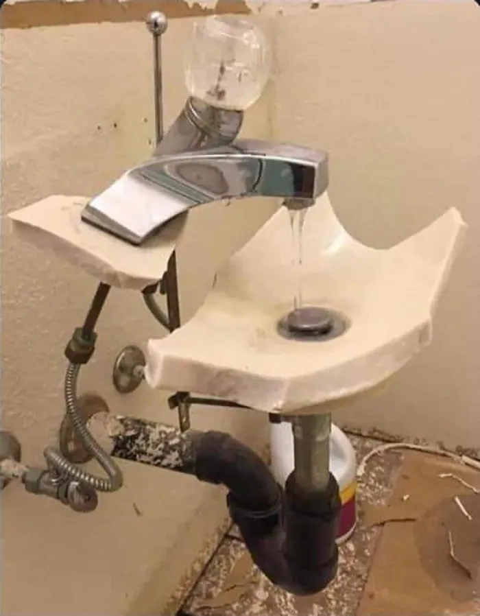 Broken sink with makeshift plumbing, ignoring OSHA safety regulations.