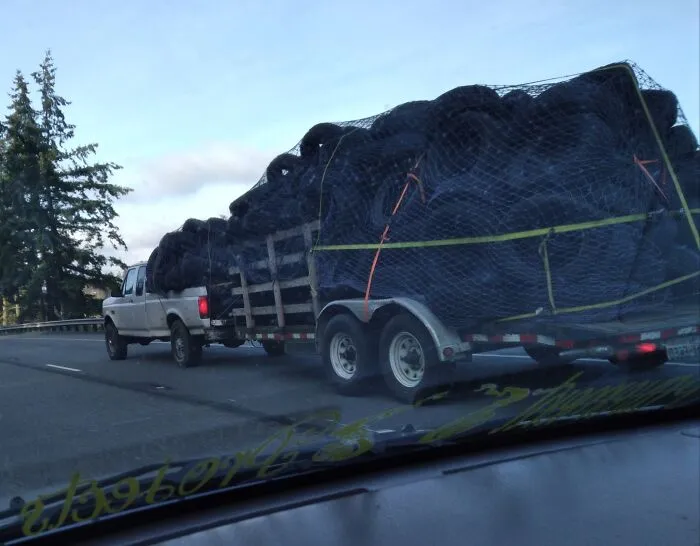 Truck hauling a large load of tires on a highway, not adhering to OSHA safety regulations.