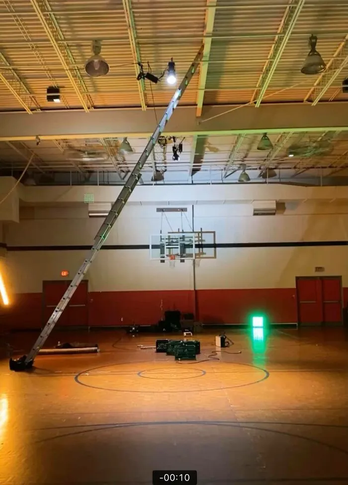 Extreme ladder setup in gymnasium, defying OSHA safety regulations.