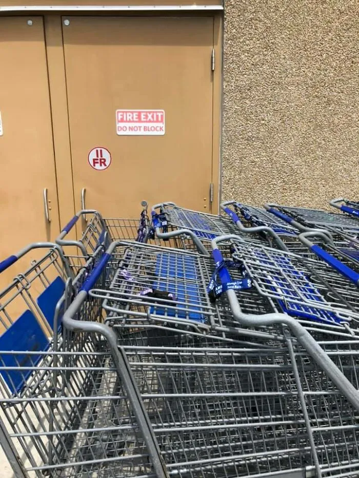 Blocked fire exit with shopping carts, ignoring OSHA safety regulations.