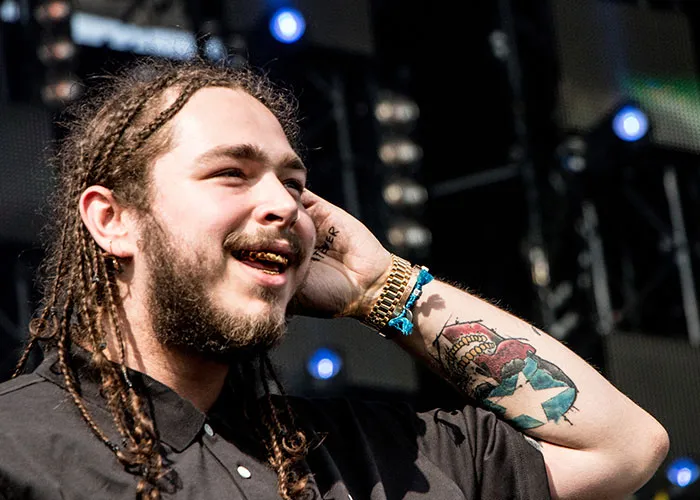 Smiling man with dreadlocks and tattoos on arm performing on stage, showing how some became very arrogant before fame.
