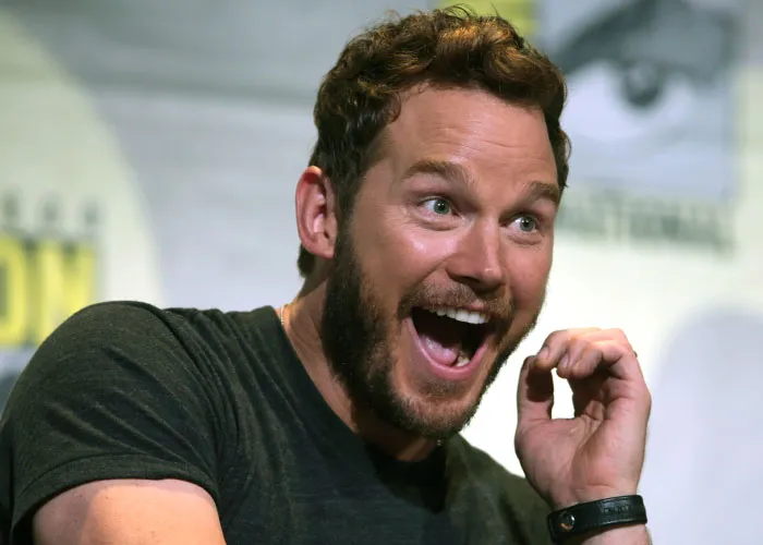 Man with beard smiling widely and expressing excitement while talking about celebrities before they were famous.