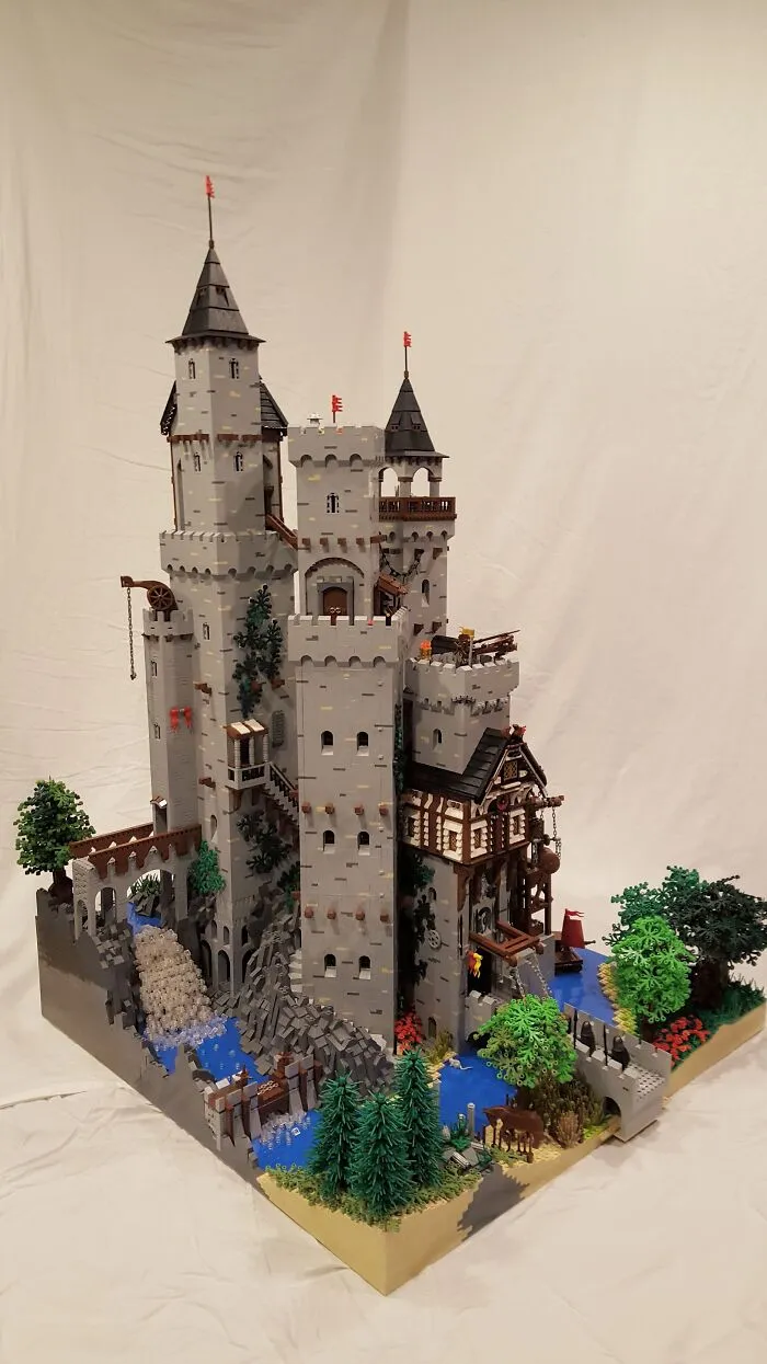 Detailed LEGO castle build with water features and trees, showcasing one of the most incredible LEGO builds and real works of art.