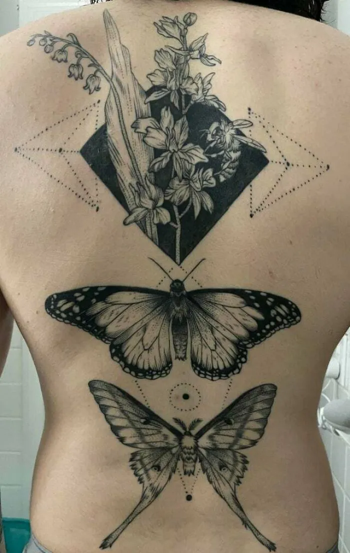 Back tattoo featuring intricate trippy designs with flowers, geometric shapes, and butterflies.
