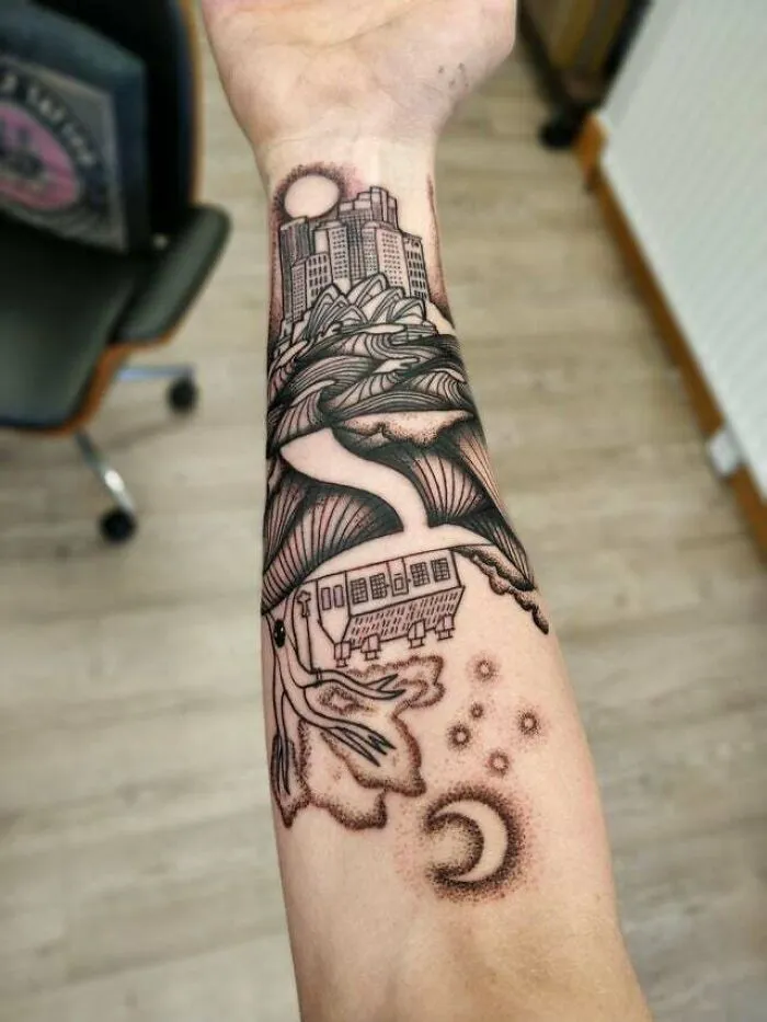 Trippy tattoo of surreal cityscape and nature scene on forearm, blending buildings and cosmic elements.
