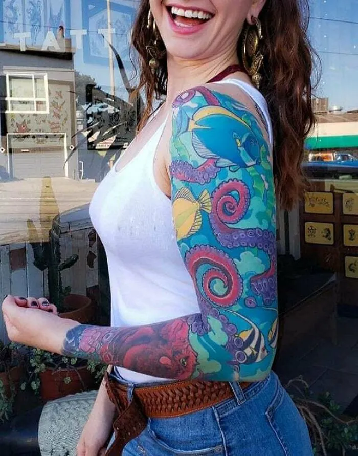 Woman showcasing a vibrant psychedelic tattoo sleeve featuring colorful sea creatures.